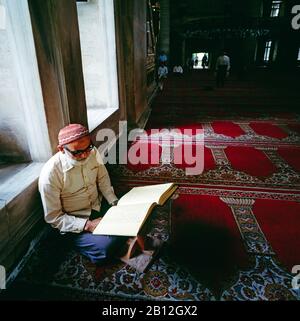 Alter Mann, der das heilige Buch des Korans in der Fatih-Moschee, Istanbul, Türkei liest Stockfoto