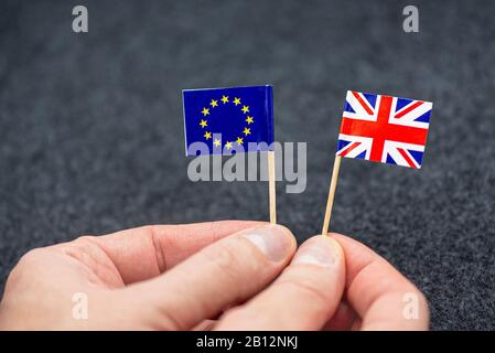 Man hält kleine Papierfahnen der EU und Großbritanniens als Symbol für BREXIT, Konzeptbild Stockfoto