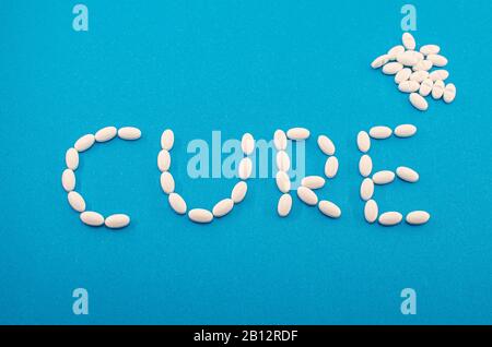 Medizinische weiße Pillen, Tabletten, die das Wort Heilung auf blauem Hintergrund bilden. Medizin, Drogenbehandlung von Krankheiten. Konzept der chinesischen Coronavirus Heilung. Stockfoto