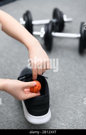 Legen Sie einen frischeren Ball des Schuhs mit Hanteln im Hintergrund in den Trainingsschuh. Konzept zur Vermeidung von unangenehmem Geruch nach Aktivität. Stockfoto