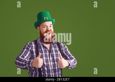 Glücklicher St. Patricks Tag. Fetter lustiger Mann in einem grünen Hut lächelt auf einem grünen Hintergrund Patricks Day. Stockfoto