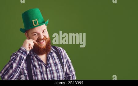 Glücklicher St. Patricks Tag. Fetter lustiger Mann in einem grünen Hut lächelt auf einem grünen Hintergrund Patricks Day. Stockfoto