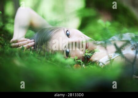 Mädchen liegt auf dem Waldboden, Porträt Stockfoto