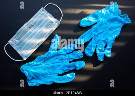Chirurgische Masken, Einweg- und medizinische Handschuhe Mit Gesichtsmaske auf schwarzem Hintergrund Stockfoto