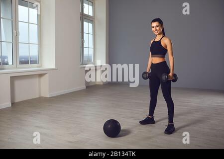 Das Mädchen geht mit einem medizinischen Ball in den Sport. Ein Sportmädchen übt Übungen in einem Raum im Haus aus. Stockfoto