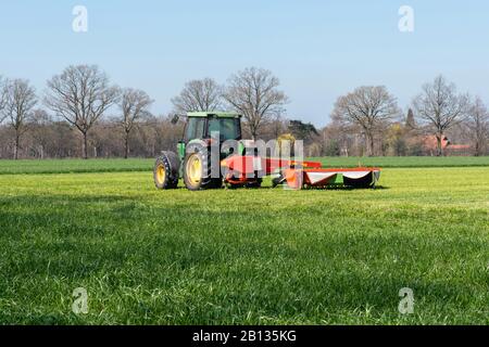 Traktor mit Mähaufbereiter auf einer teilweise gemähte Wiese Stockfoto