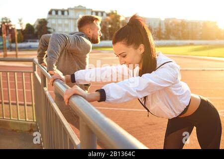 Mädchen und Mann in der Sportbekleidung wärmen sich im Stadion auf Stockfoto