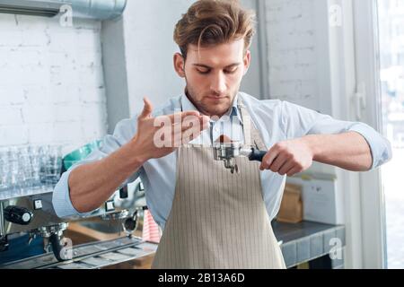 Kaffeepassion. Junger Barista in der Café-Bar, in der der Schweinefilter den Kaffee schmoren Stockfoto