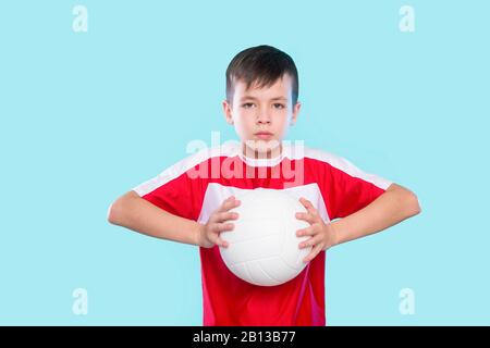 Kaukasischer Junge, der den Ball im Volleyball serviert, isoliert auf blauem Hintergrund Stockfoto