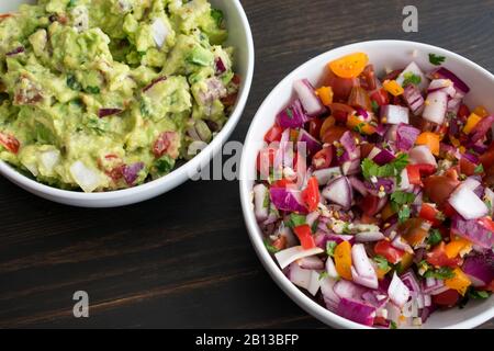 Schüsseln von Guacamole und Pico de Gallo: Zwei weiße Schüsseln mit frisch zubereitetem Guacamol und Pico de gallo (Salsa fresca) Stockfoto