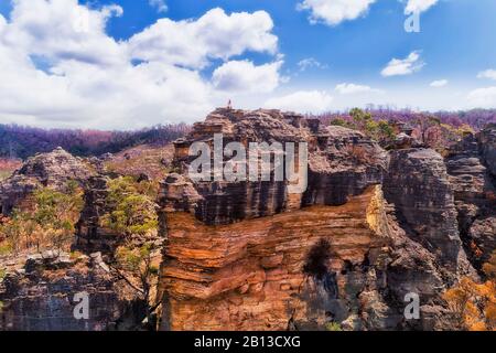 Scharfe Steilklippe aus Sandsteinfelsen in den Blue Mountains in Australien. Einsames Mädchen sitzt oben. Stockfoto