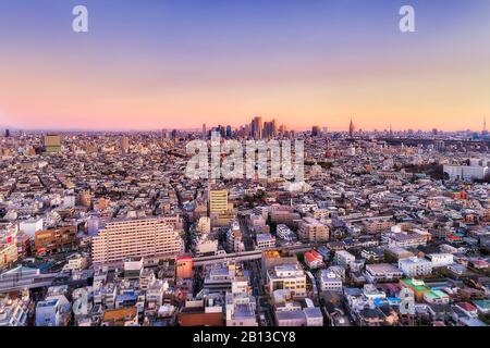 Luftbild über die entwickelten Tokioter Stadtvororte um Shibuya bei Sonnenaufgang mit weichem, rosafarbenem Sonnenlicht. Stockfoto