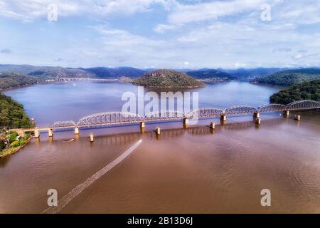 Hill Ranges am Ufer des Flusses Hawkesbury nahe dem Fischerdorf Brooklyn mit langer Eisenbahnbrücke, die Greater Sydney mit der Central Coast verbindet. Stockfoto