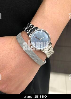 Silberfarbene Metalluhr mit blauem Perlmuttgesicht und Rauten und Armband am Handgelenk der Dame Stockfoto