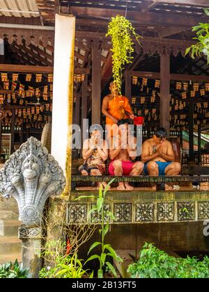 Drei Menschen erhalten während des Wasserfestes einen Wassersegnung von einem Mönch in einem buddhistischen Tempel in Kambodscha. Angkor Wat Archäologischer Park, Siem Reap, C. Stockfoto