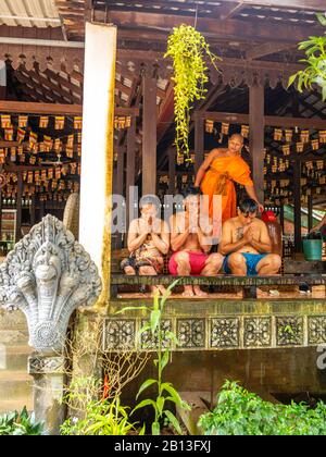 Drei Menschen erhalten einen Segen von einem buddhistischen Mönch als Teil des jährlichen Wasserfestes in einem Tempel im Archäologischen Park Angkor Wat, KH Stockfoto