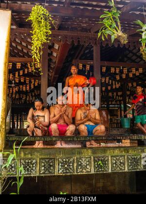 Drei Menschen erhalten während des Wasserfestes einen Wassersegnung von einem Mönch in einem buddhistischen Tempel in Kambodscha. Angkor Wat Archäologischer Park, Siem Reap, C. Stockfoto