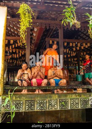 Drei Menschen erhalten während des Wasserfestes einen Wassersegnung von einem Mönch in einem buddhistischen Tempel in Kambodscha. Angkor Wat Archäologischer Park, Siem Reap, C. Stockfoto