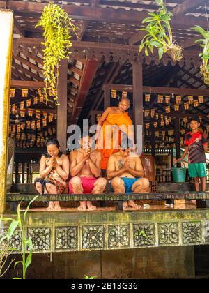 Drei Menschen erhalten während des Wasserfestes einen Wassersegnung von einem Mönch in einem buddhistischen Tempel in Kambodscha. Angkor Wat Archäologischer Park, Siem Reap, C. Stockfoto