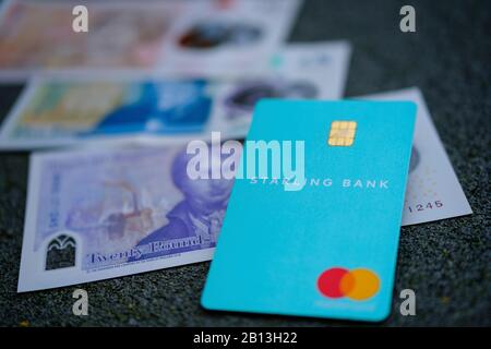 Karte der Starling Bank und unscharfes Bargeld im Hintergrund. Selektiver Fokus. Stockfoto