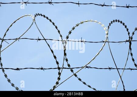 Stacheldraht auf Zaun gegenüber dem klaren blauen Himmel. Stockfoto