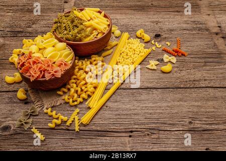 Verschiedene Nudelarten in Keramikschalen. Traditionelles italienisches Essen, gesundes Esskonzept. Rustikaler Holztisch, Kopierraum Stockfoto