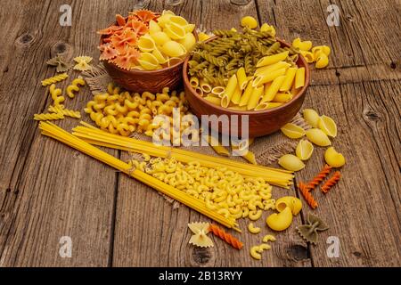 Verschiedene Nudelarten in Keramikschalen. Traditionelles italienisches Essen, gesundes Esskonzept. Rustikaler Holztisch, Kopierraum Stockfoto