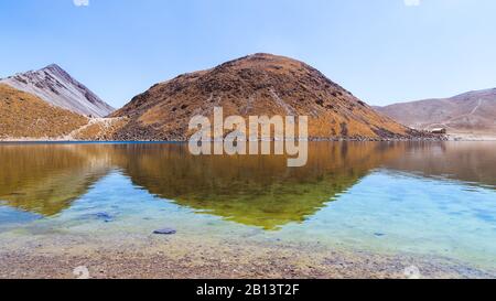 Ein See mit kristallklarem Wasser, umgeben von Bergen und einem blauen Himmel, an einem brighty-tag Stockfoto