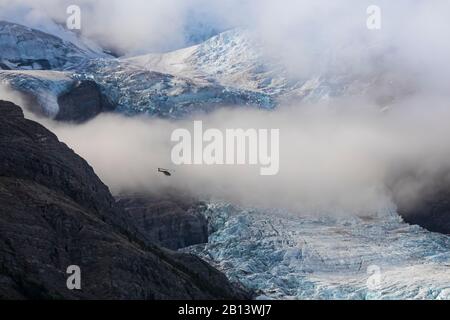 Dramatischer Blick auf einen Sightseeing-Hubschrauber über dem Berg-Gletscher im Mount Robson Provincial Park, British Columbia, Kanada Stockfoto