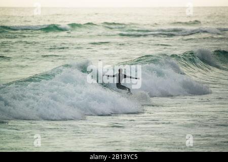 Surfer bei Sonnenuntergang, Big Bay, Kapstadt, Südafrika Stockfoto