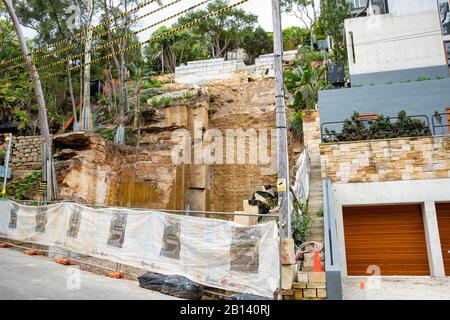 Australien, tiefe Grabung in Felsen, um ein neues Luxusheim in Palm Beach, Sydney, zu bauen, angrenzende Häuser, die während der Grabung unterstützt wurden Stockfoto