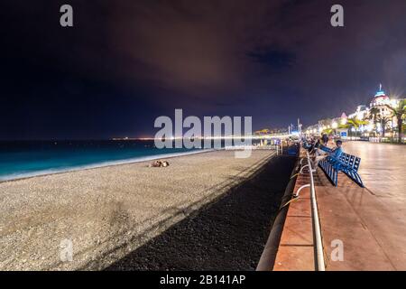 Nachtaufnahmen entlang der Promenade des Anglais, während Touristen einen Abend entlang der Bucht Von Angles an der französischen Riviera genießen. Stockfoto