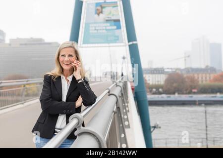 Geschäftsfrau telefoniert auf einer Brücke Stockfoto