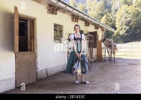 Bauer mit Dirndl trägt eine Melkmaschine Stockfoto