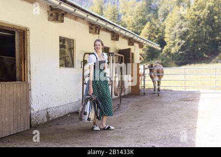 Bauer mit Dirndl trägt eine Melkmaschine Stockfoto