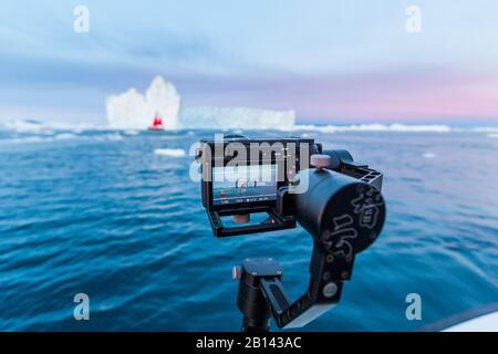 Kamera auf Stativ fotografiert und Segelboot Eisberge in der Diskobucht auf Mittsommer, Grönland Stockfoto