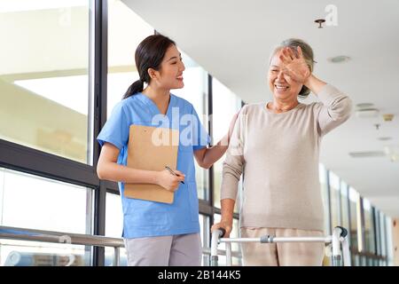 Asiatische Seniorin entfernt Schweiß von der Stirn während der körperlichen Therapiesitzung im Reha-Zentrum Stockfoto