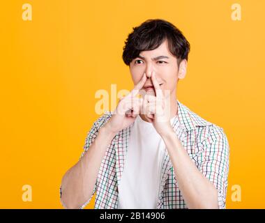 Der junge Mann hält die Nase Stockfoto