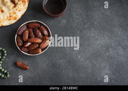 Traditionelles Ramadan, iftar Mahlzeit - Datumsfrüchte, ramadan frisches Brot und Wasser auf schwarzem Tisch, Draufsicht, Kopierraum. Ramadan Kareem Konzept. Stockfoto