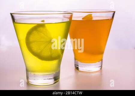 Zitronengelb und orangefarbenes Gelee in Gläsern auf weißem Hintergrund. Stockfoto