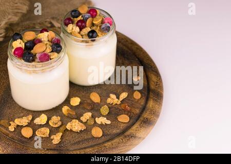 Zwei Gläser Joghurt, Granola und Beeren auf einem Holzbrett. Kopierbereich Stockfoto