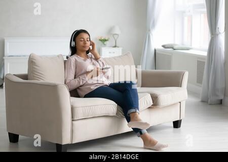 Biracial Woman entspannen auf der Couch Musik hören mit Cell Stockfoto