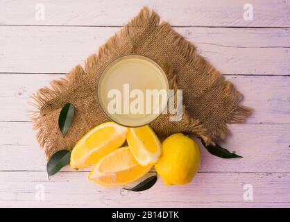 Gasse mit frisch gepresstem Zitronensaft auf weißem Holzhintergrund. Draufsicht. Stockfoto