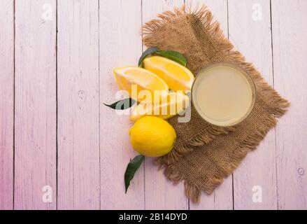 Gasse mit frisch gepresstem Zitronensaft auf weißem Holzhintergrund. Draufsicht. Kopierbereich. Stockfoto