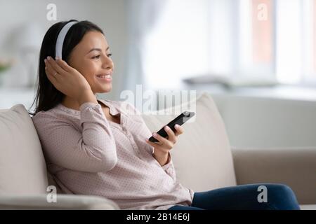 Fröhliche Frau im Kopfhörer genießen Musik auf dem Smartphone Stockfoto