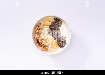 Smoothie-Schüssel mit Bananen, Chia, Sesam und Müsli auf weißem Grund Stockfoto