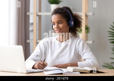 Afrikanische Mädchen tragen Kopfhörer Studie mit Skype-Lehrer auf Laptop Stockfoto