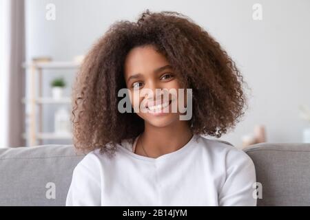 Kopfschuss eines lächelnden afrikanischen Mädchens, das zu Hause die Kamera betrachtet Stockfoto