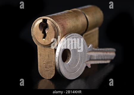 Patentschloss und Schlüssel aus Messing. Zubehör zur Befestigung der Vordertüren im Haushalt. Dunkler Hintergrund. Stockfoto