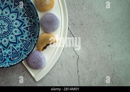 Mehrfarbige japanische Mochi in Reisteig und auf einem schönen Teller und Betonhintergrund. Traditionelles japanisches Dessert. Stockfoto